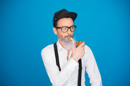 man wearing shirt and hat smoking e-pipe
