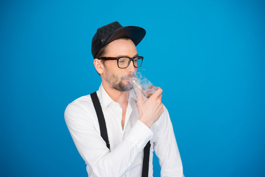 man wearing shirt and hat smoking e-pipe