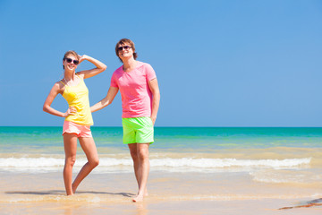 Couple in bright clothes posing on tropical beach. Honeymoon