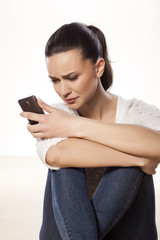 Naklejka premium miserable and sad young woman looking at her mobile phone