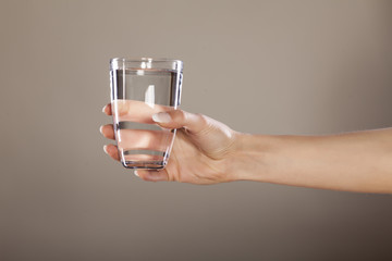 woman's hand holding a glass of clean water - obrazy, fototapety, plakaty