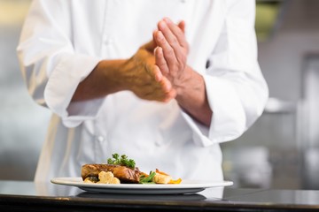 Obraz na płótnie Canvas Mid section of a chef putting salt in kitchen