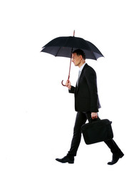 Businessman walking with umbrella and laptop bag