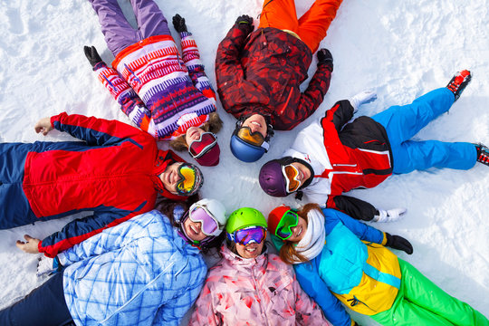 Funny happy snowboarders lying in a circle