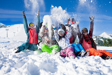 Funny happy friends with snowboards throwing snow