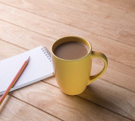 Coffee cup with notebooks and pencils.
