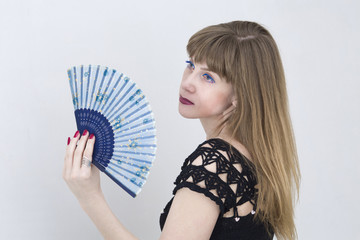 Young woman partly hidden behind a fan