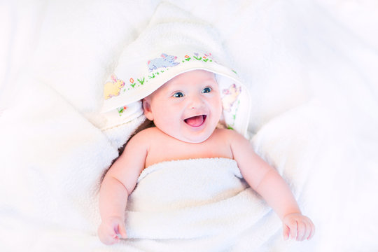 Happy laughing baby in a hand made cross stitch hooded towel