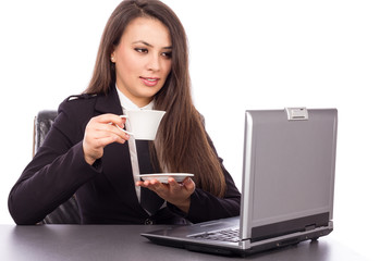 Beautiful young businesswoman drinking coffee / tea and using la