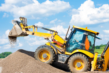 Excavator machine unloading gravel during earth moving works