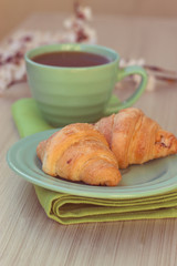 Cup of tea and croissants near blossoming branches