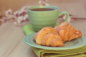 Cup of tea and croissants near blossoming branches