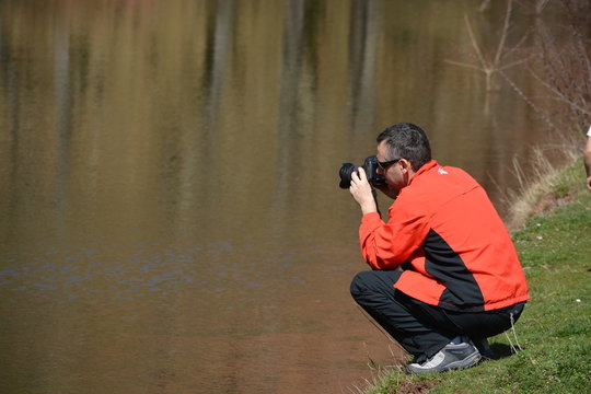 Fotografo fotografiando en un estanque en un dia de primavera