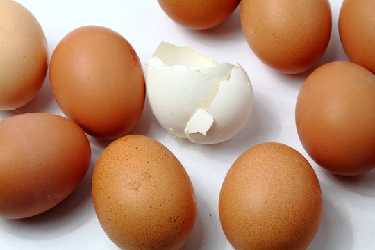 Weißes zerbrochenes Ei unter braunen Eiern
