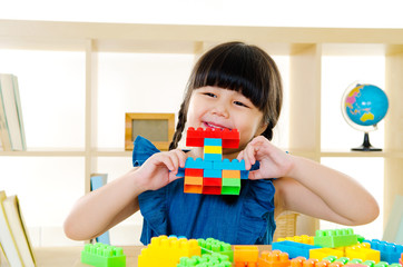 Asian kid piling up building blocks