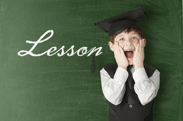 Cheerful little boy on blackboard. Looking at camera