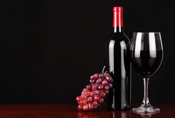 Fotobehang Wine Bottle and Glass of Red Wine with Fresh Grapes over black © Guzel Studio