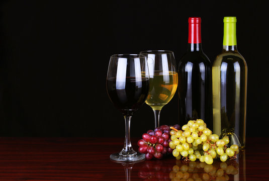 Wine Bottles and Glasses of Wine over black background.