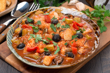 Fish stew with olives in tomato sauce on a plate