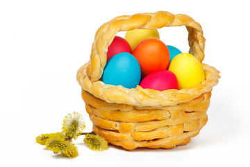 Baked basket with Easter colored eggs and bunch of willow