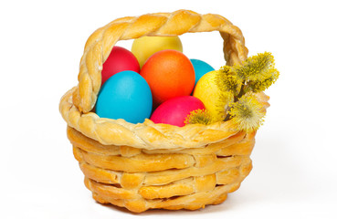 Baked basket with Easter colored eggs and bunch of willow