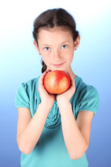 Portrait of beautiful little girl with apple on blue background