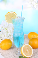 Glass of cocktail on table on light blue background