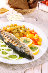 Delicious grilled fish on plate on table close-up