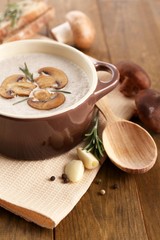 Mushroom soup in pot, on wooden background