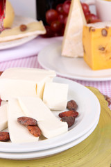 Assorted cheese plate on pink tablecloth background, close-up
