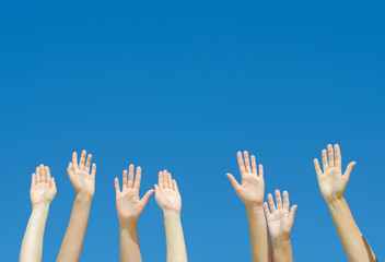 Many hands raised up against the blue sky.
