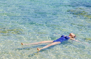 Pretty woman swimming in transparent turquoise sea.