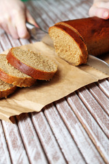 Female hands cutting bread on wooden board, close-up