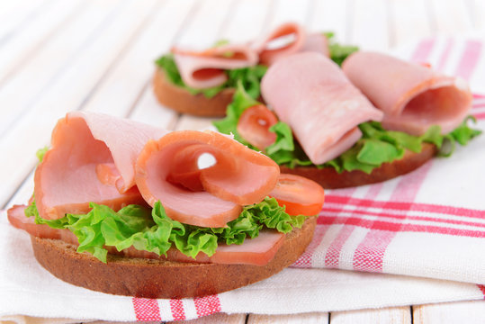 Delicious sandwiches with lettuce and ham on table close-up