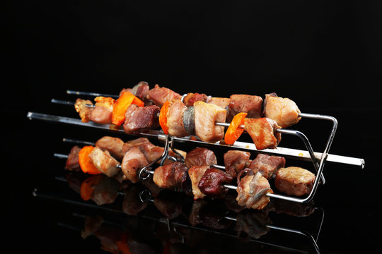 Pork kebab on grill on black background