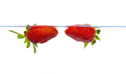 fresh strawberry dropped into water with splash on white backgrounds