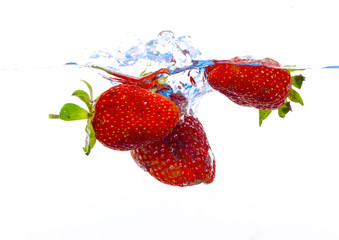 fresh strawberry dropped into water with splash on white backgrounds