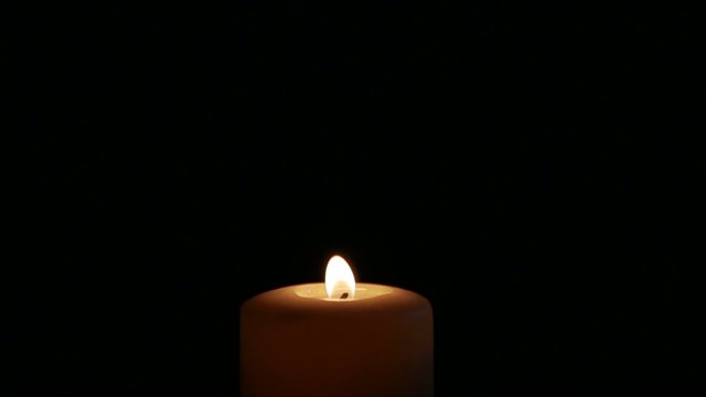 Candle goes on black background. Slow motion