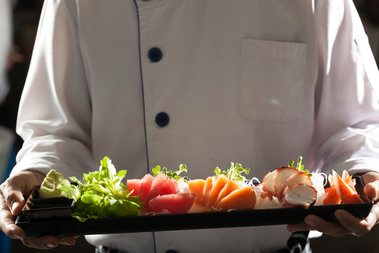 sashimi, a chef uniform holding a dish of Japanese Sashimi