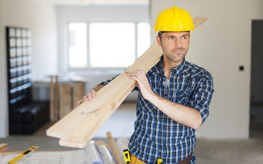 Manley construction worker holding wood planks
