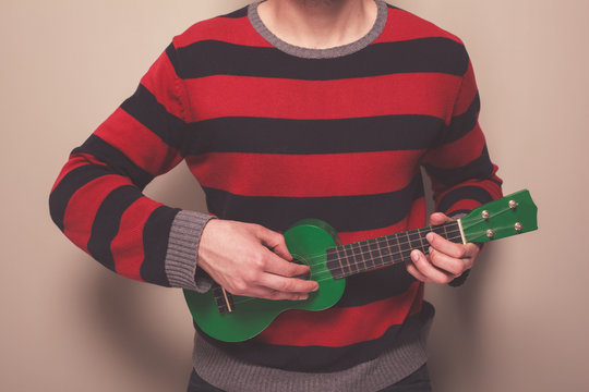 Man in striped jumper playing ukulele
