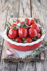 Fresh cherry tomatoes with thyme and garlic in the red bowl