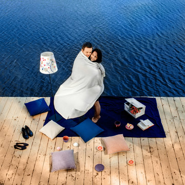 Couple Covered By Blanket Standing On Terrace Near The Water