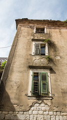 Fototapeta na wymiar Broken Old Building in Kotor with Green Shutters