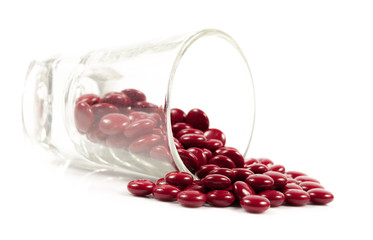 Red pills and pill bottle on white