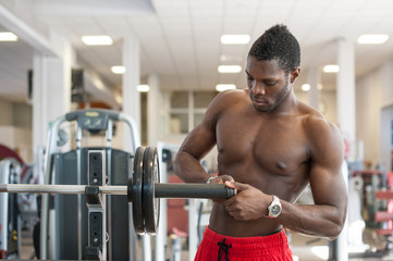 Fototapeta na wymiar Strong black man adjusting heavy lift on bar in the gym.