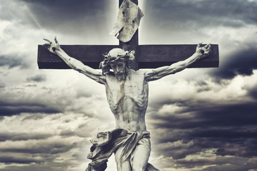 Crucifixion. Christian cross with Jesus Christ statue over storm