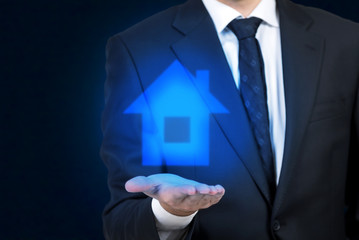 Businessman holding a hologram house icon
