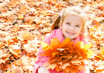 Autumn portrait of cute smiling little girl with maple leaves