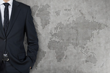 Businessman and world background wall (grey, concrete)